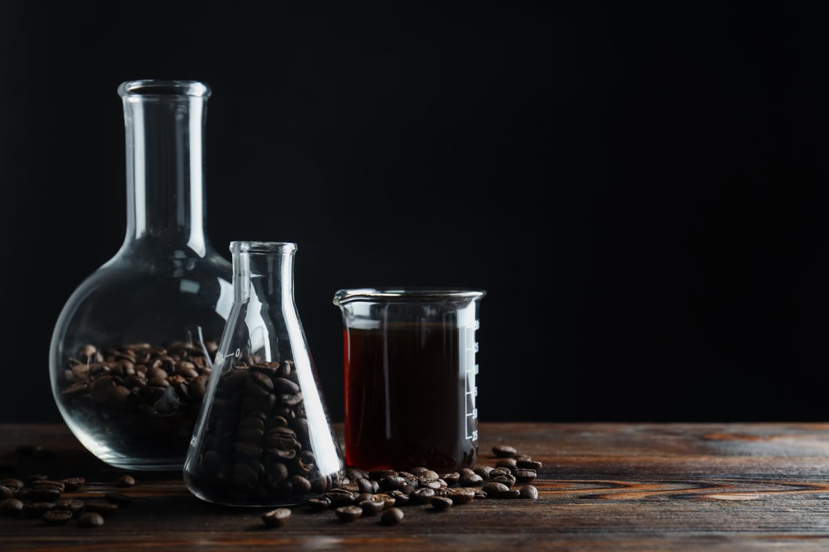 Glass flasks holding coffee and beans on a dark wooden table