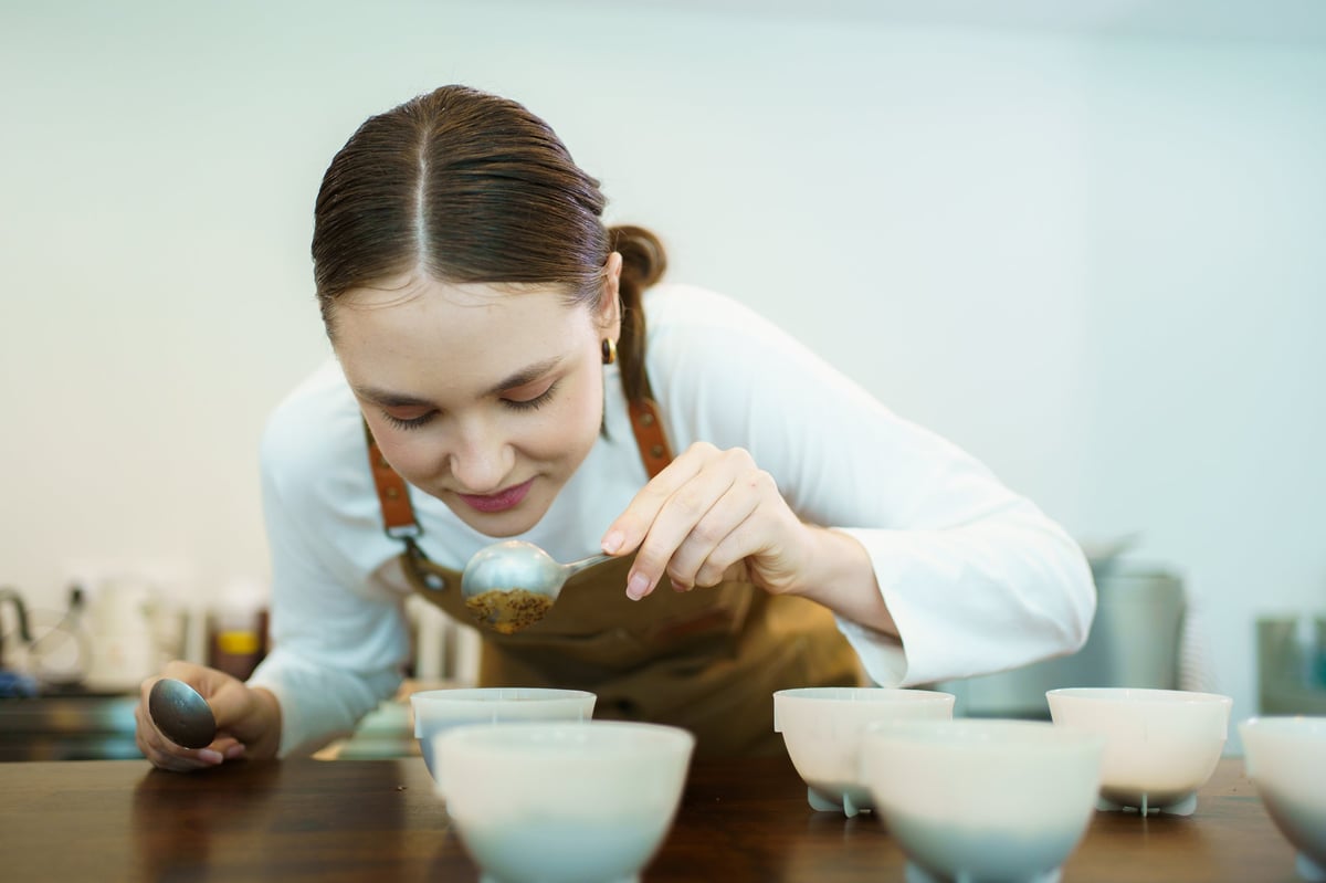 Barista evaluating ground coffee aroma with a cupping spoon