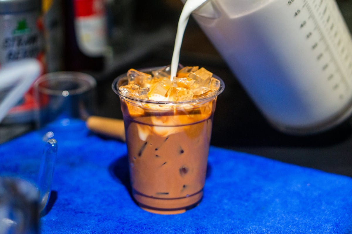 Barista pouring milk into iced espresso, creating a marble effect
