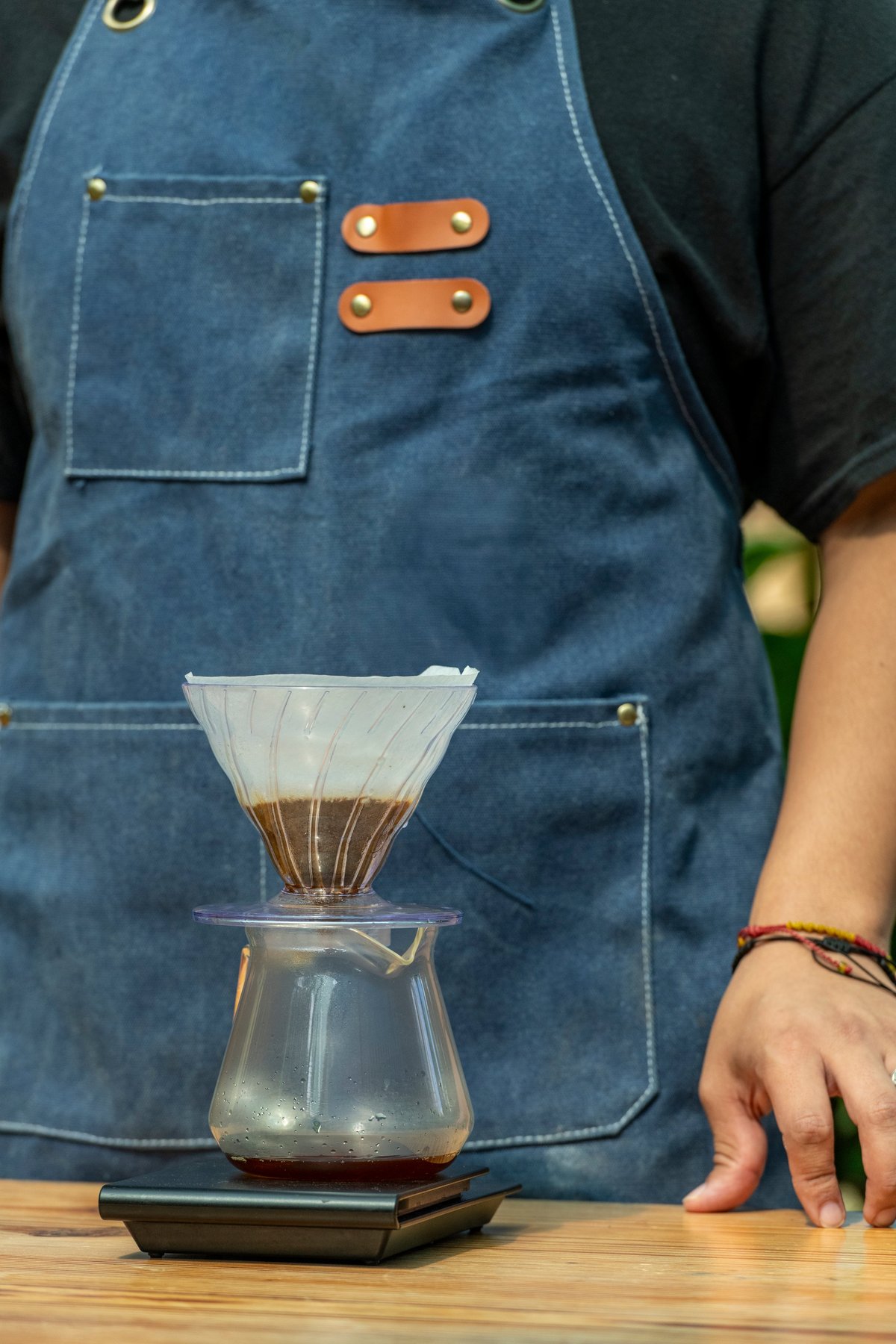 Pour-over coffee filtering into a glass server on a scale